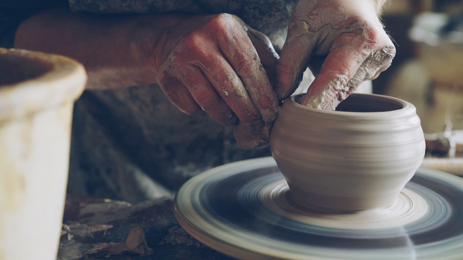 Close-up of hands molding wet clay on a spinning pottery wheel.
