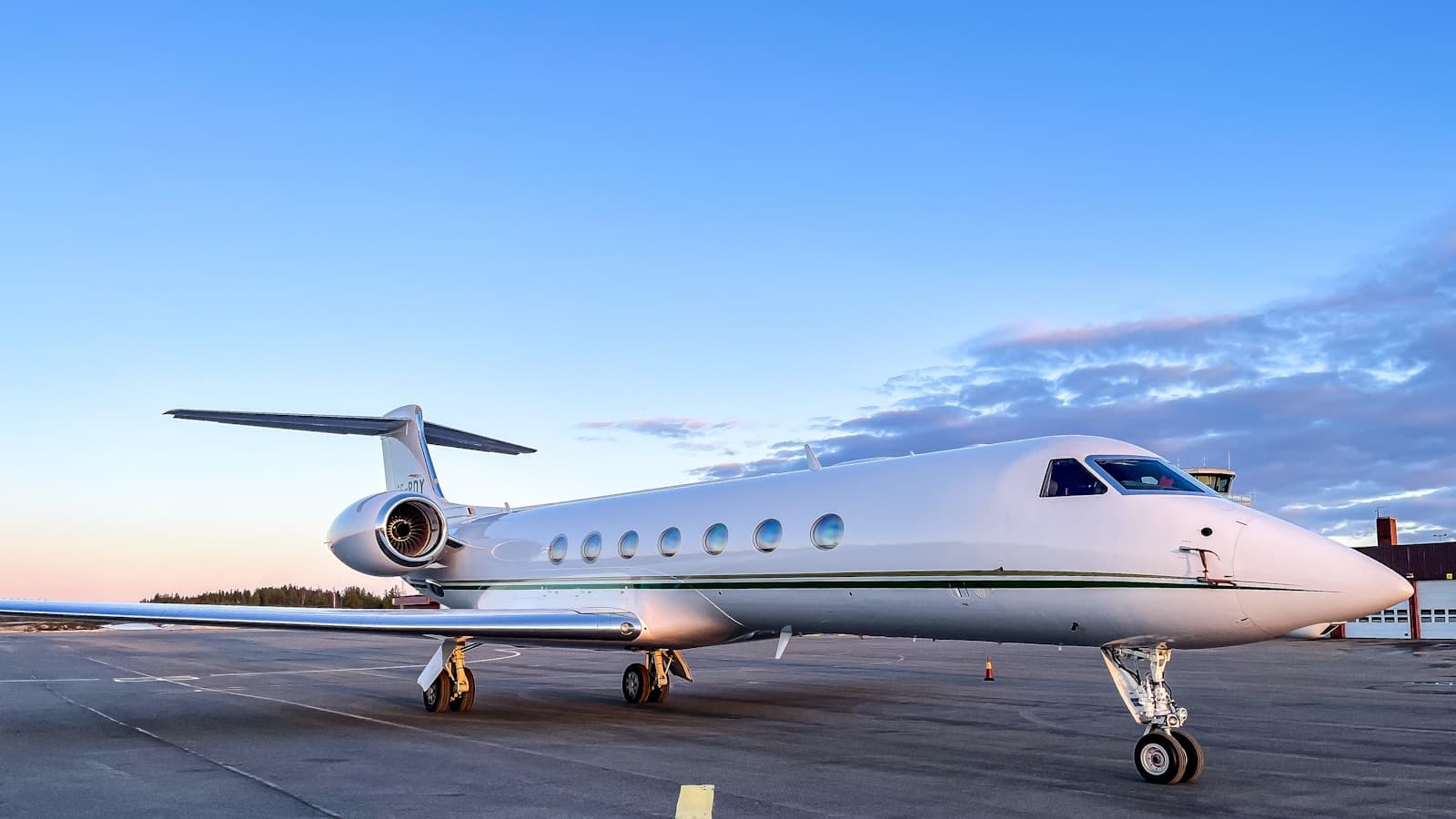 A private jet parked on tarmac at dusk, clean side profile.