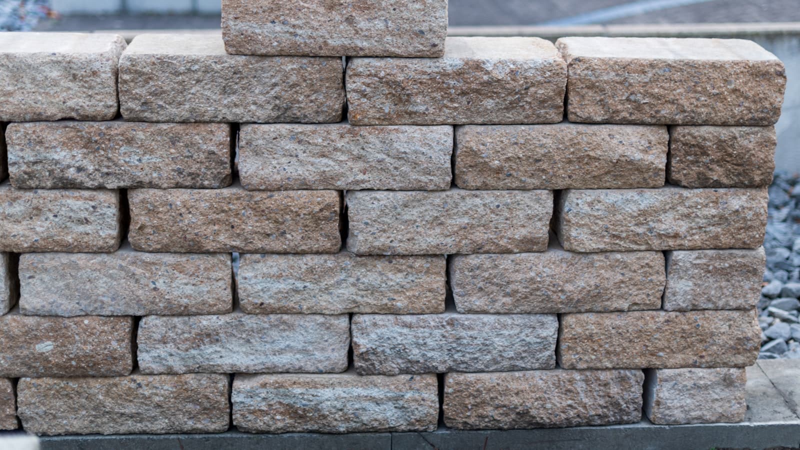 A close-up of a newly built stacked tan stone retaining wall; no faces or readable text.