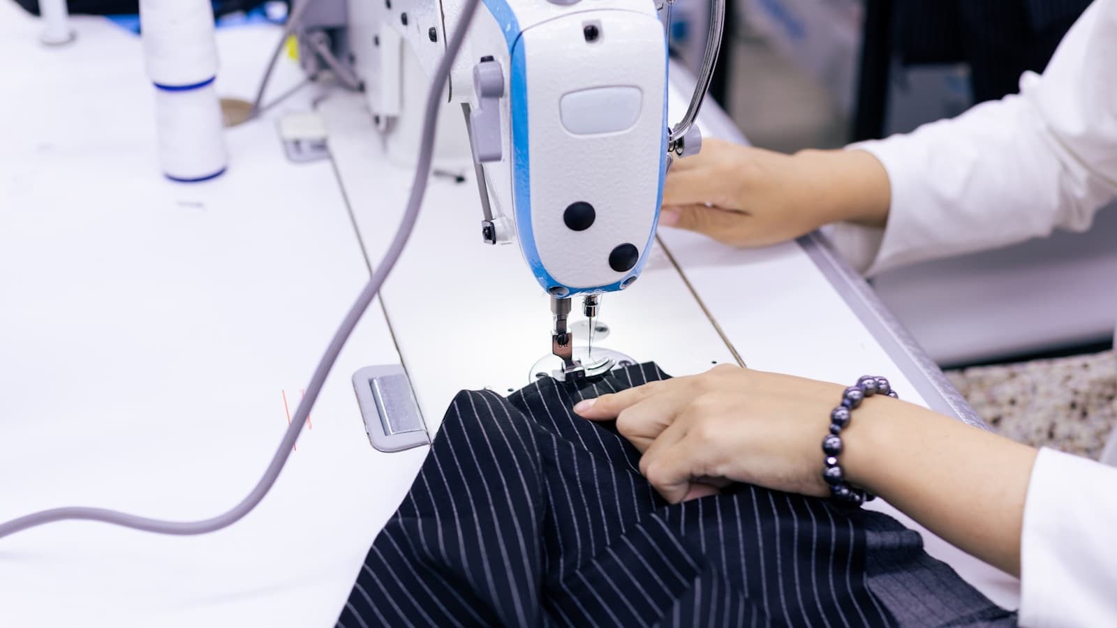 A woman's hands guiding fabric through a sewing machine.
