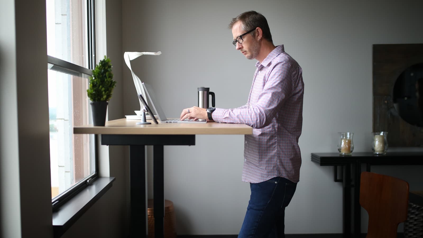 A man standing at an elevated desk in a bright modern office.