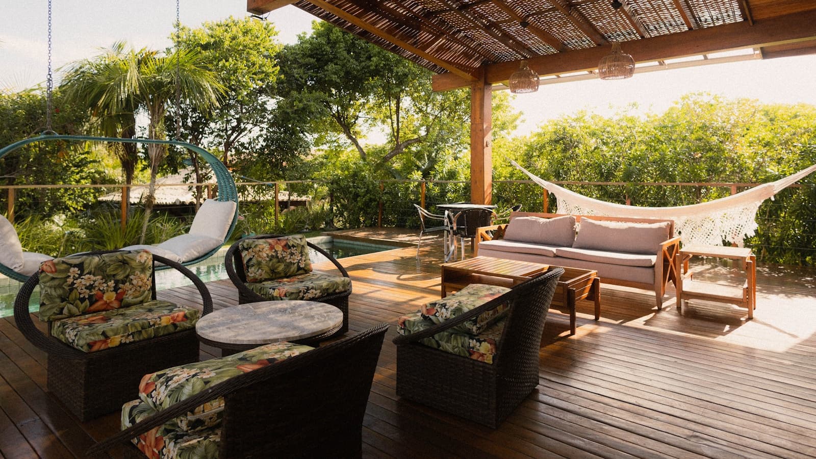 A covered patio with lounge seating, a hammock, and a pool view.