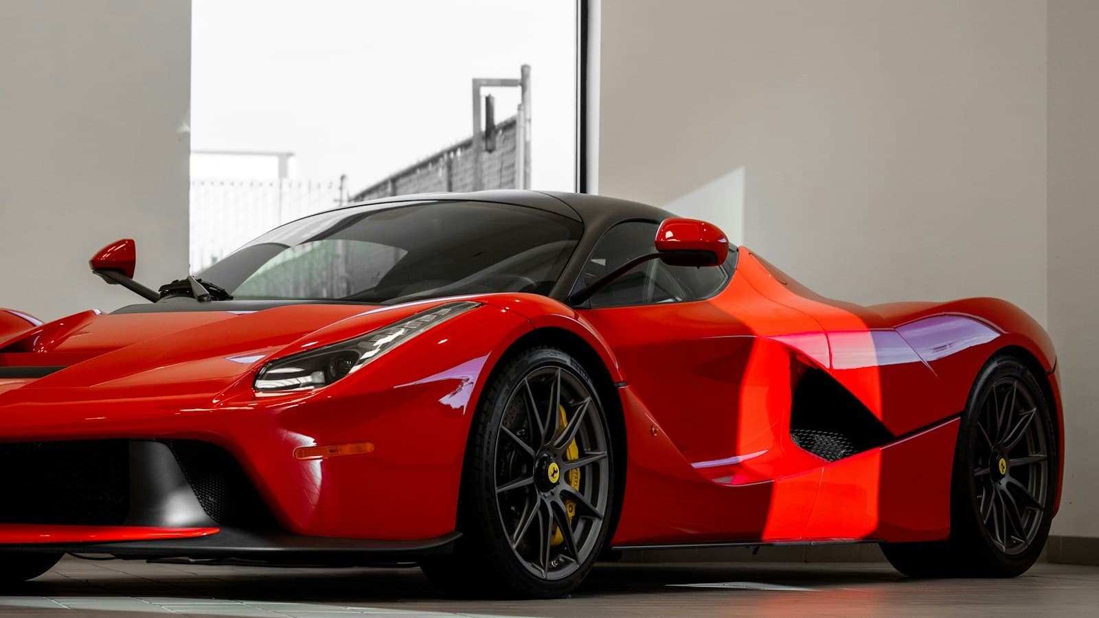 A red Ferrari LaFerrari parked in a showroom, with an empty cabin, no people, and only a small non-legible badge on the hood.