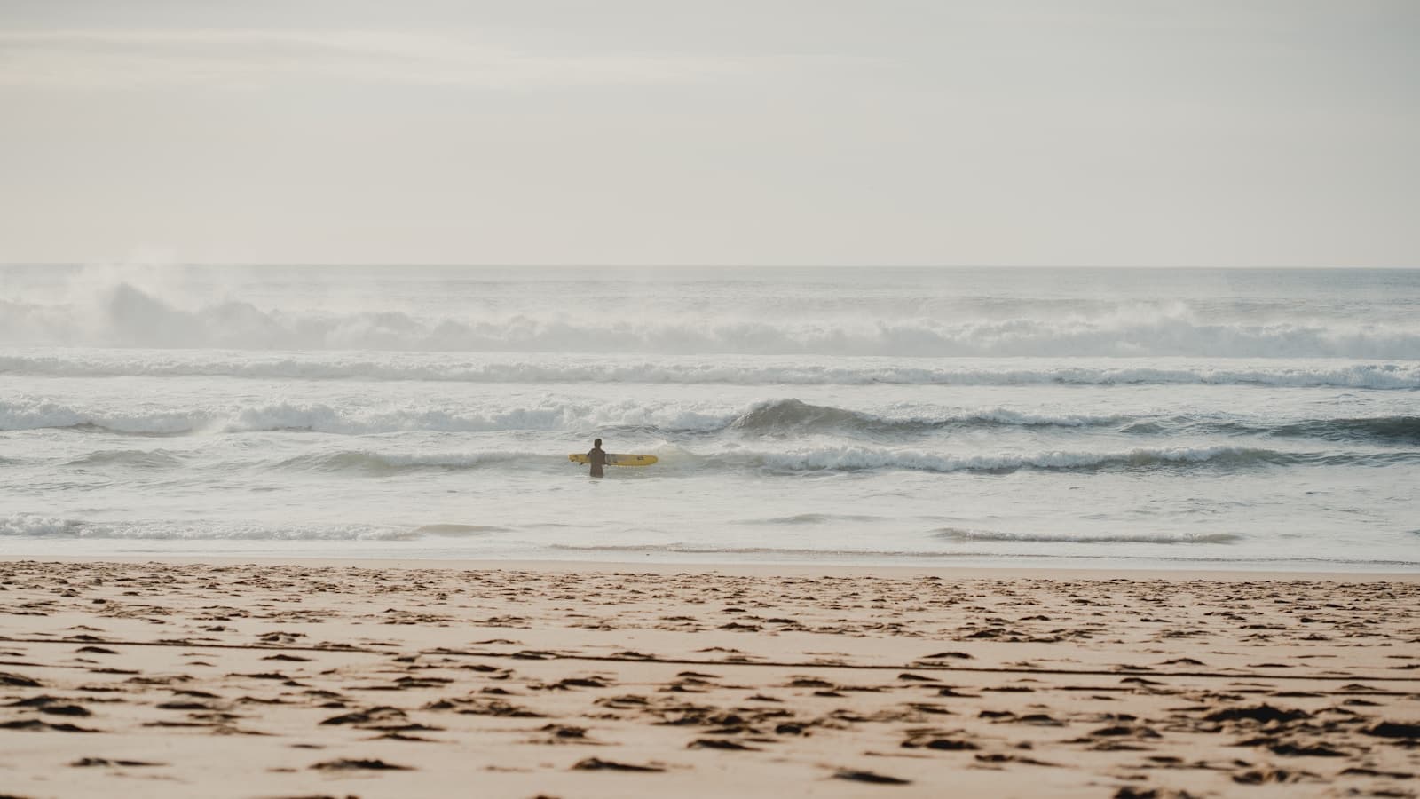 A surfer paddling out on a surfboard through ocean waves.