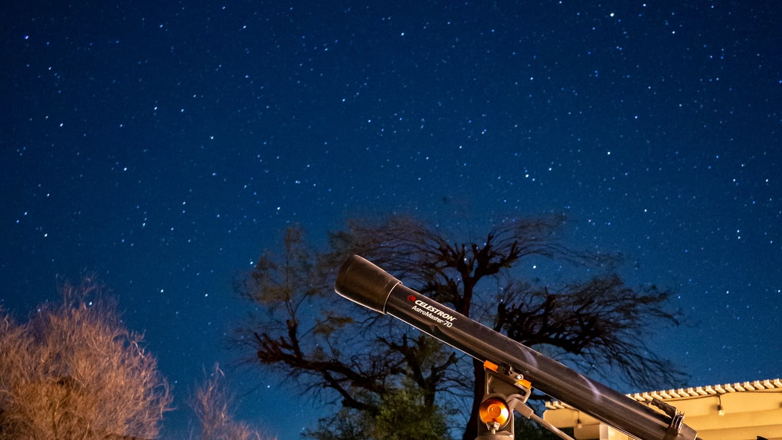 A telescope pointed up at a star-filled night sky.