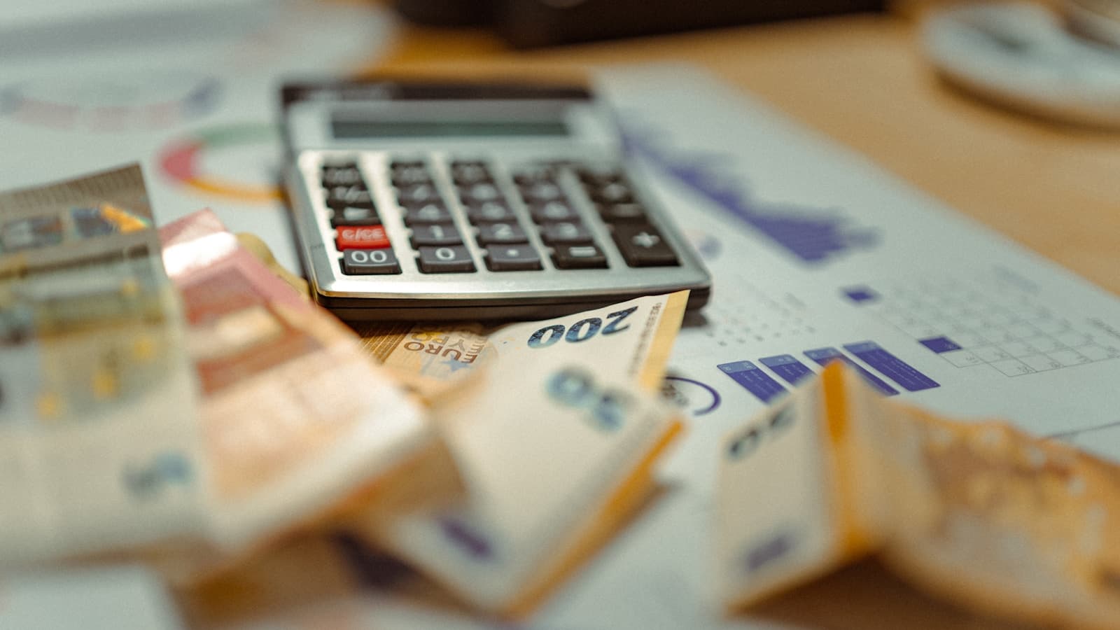 A calculator sitting on top of a stack of cash and paperwork.