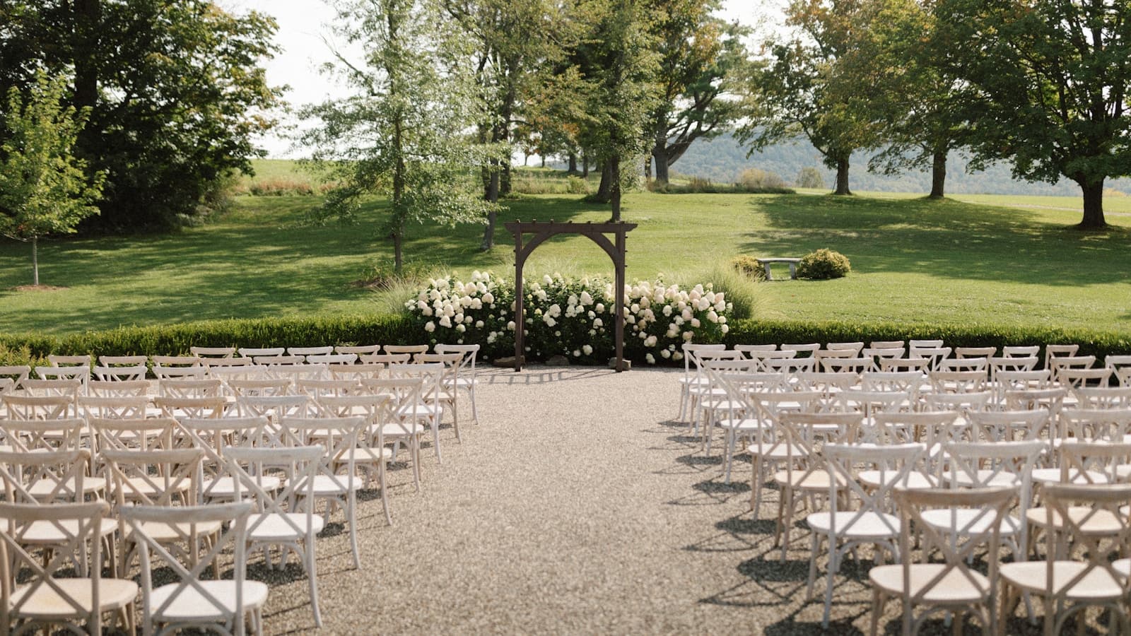 An outdoor wedding ceremony setup with rows of white chairs.