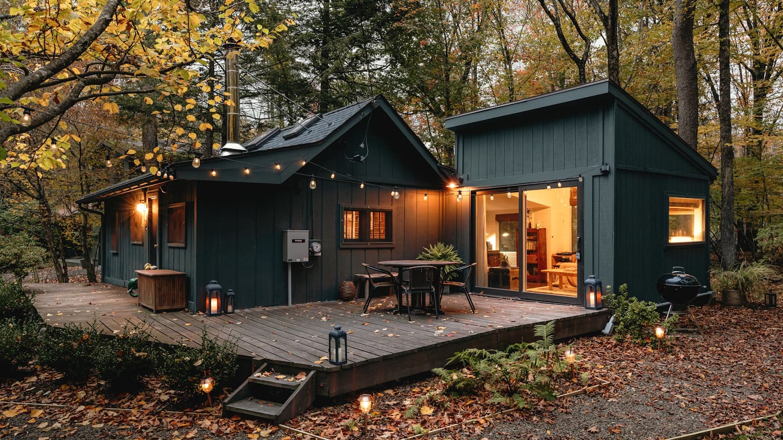 A small cabin with a deck tucked into the woods.