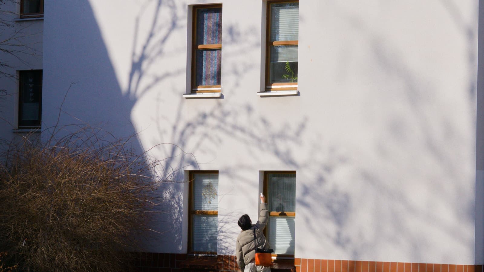 A person cleaning a window on a plain residential building exterior.