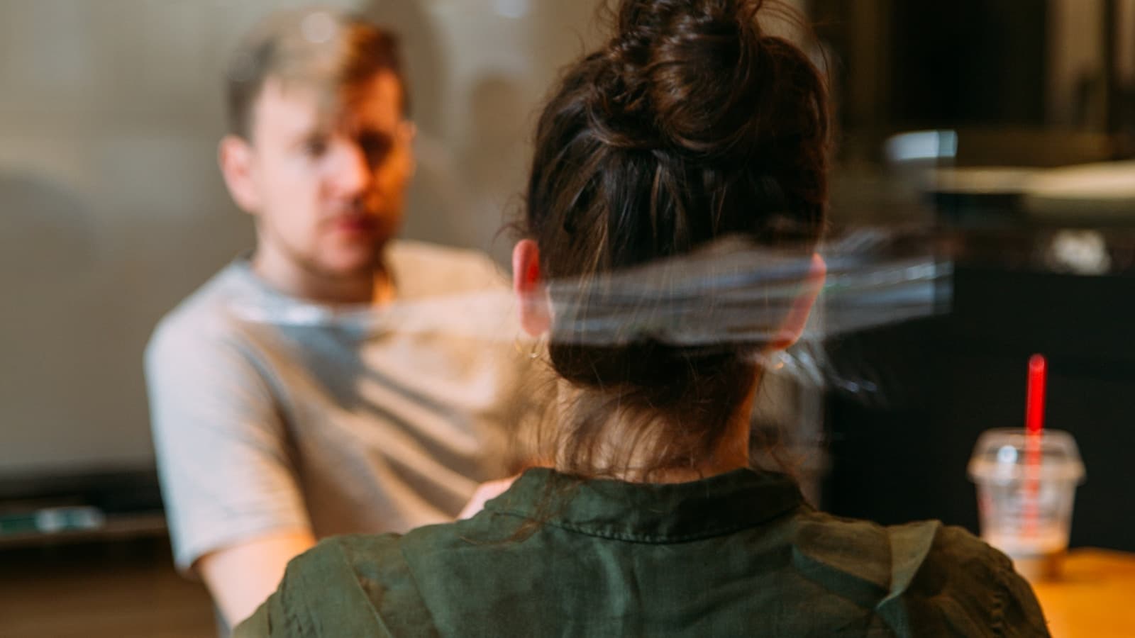 Two people in a mediation-style meeting at a cafe/office table.