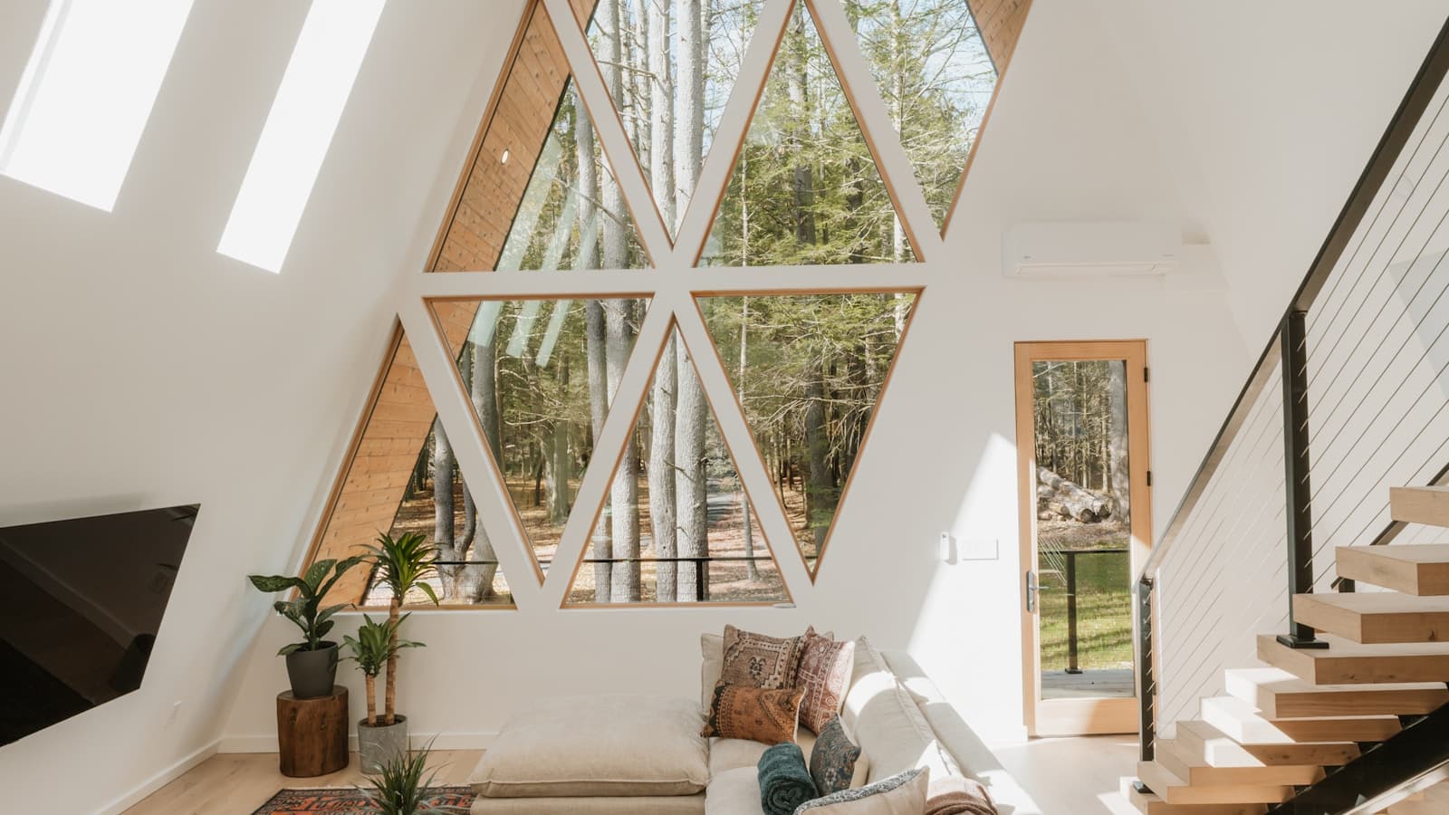 A bright, high-ceilinged living room with a triangular window wall.