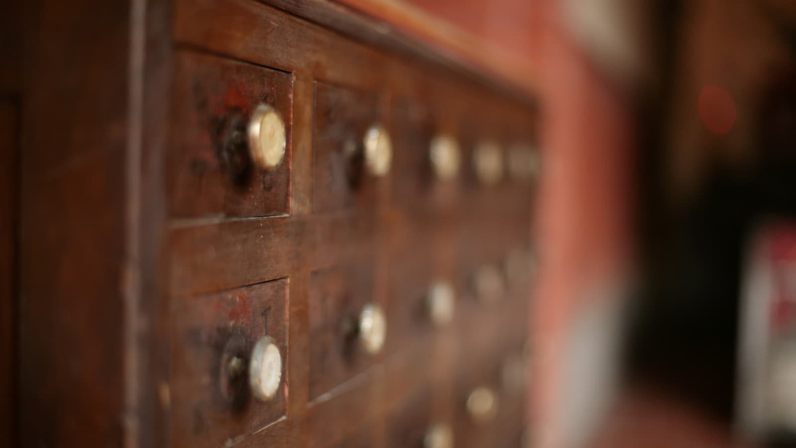 Close-up of an antique wooden apothecary-style cabinet with brass drawer pulls.