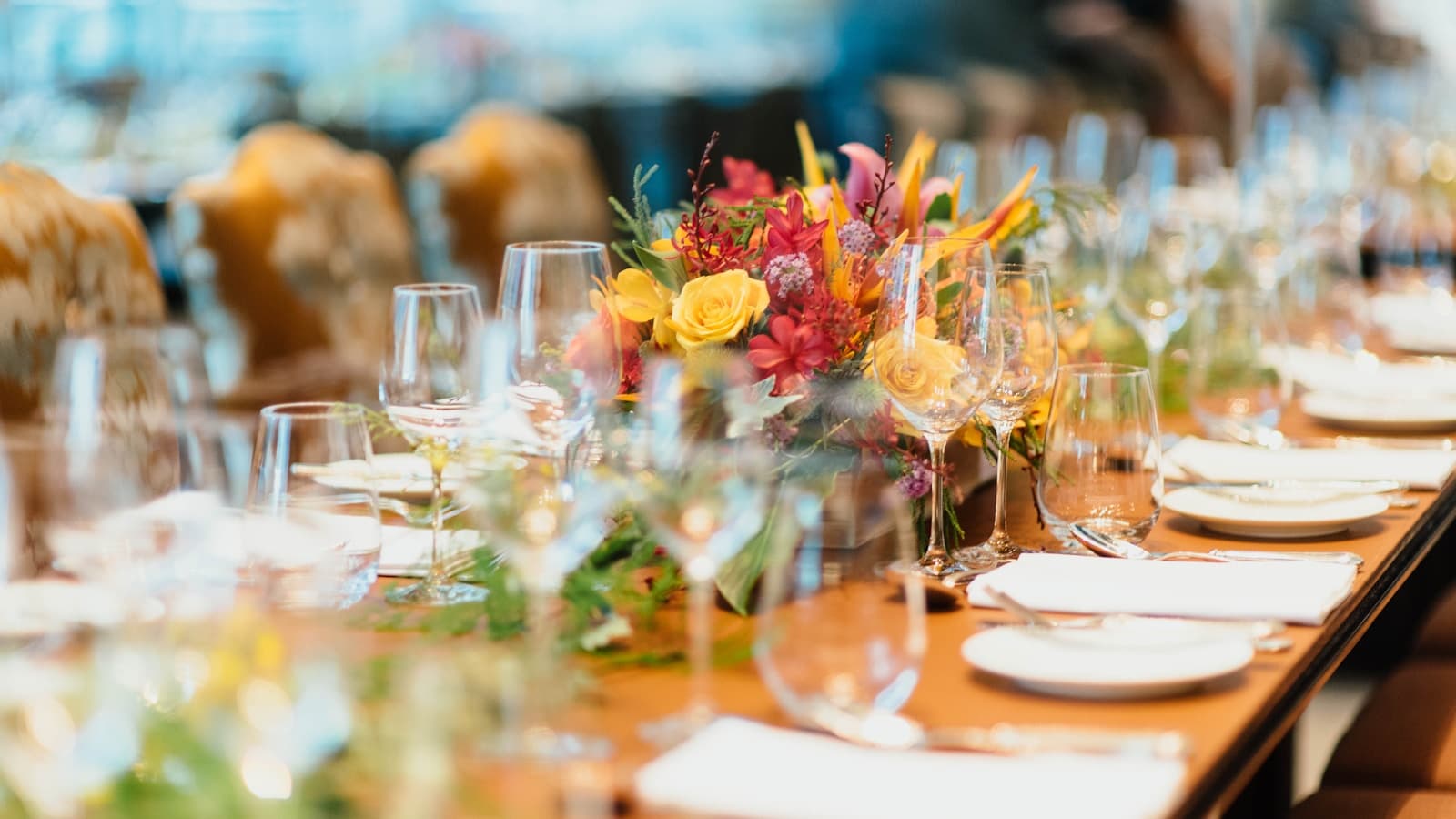 A styled elegant table setting with a floral centerpiece, glassware, and place settings.