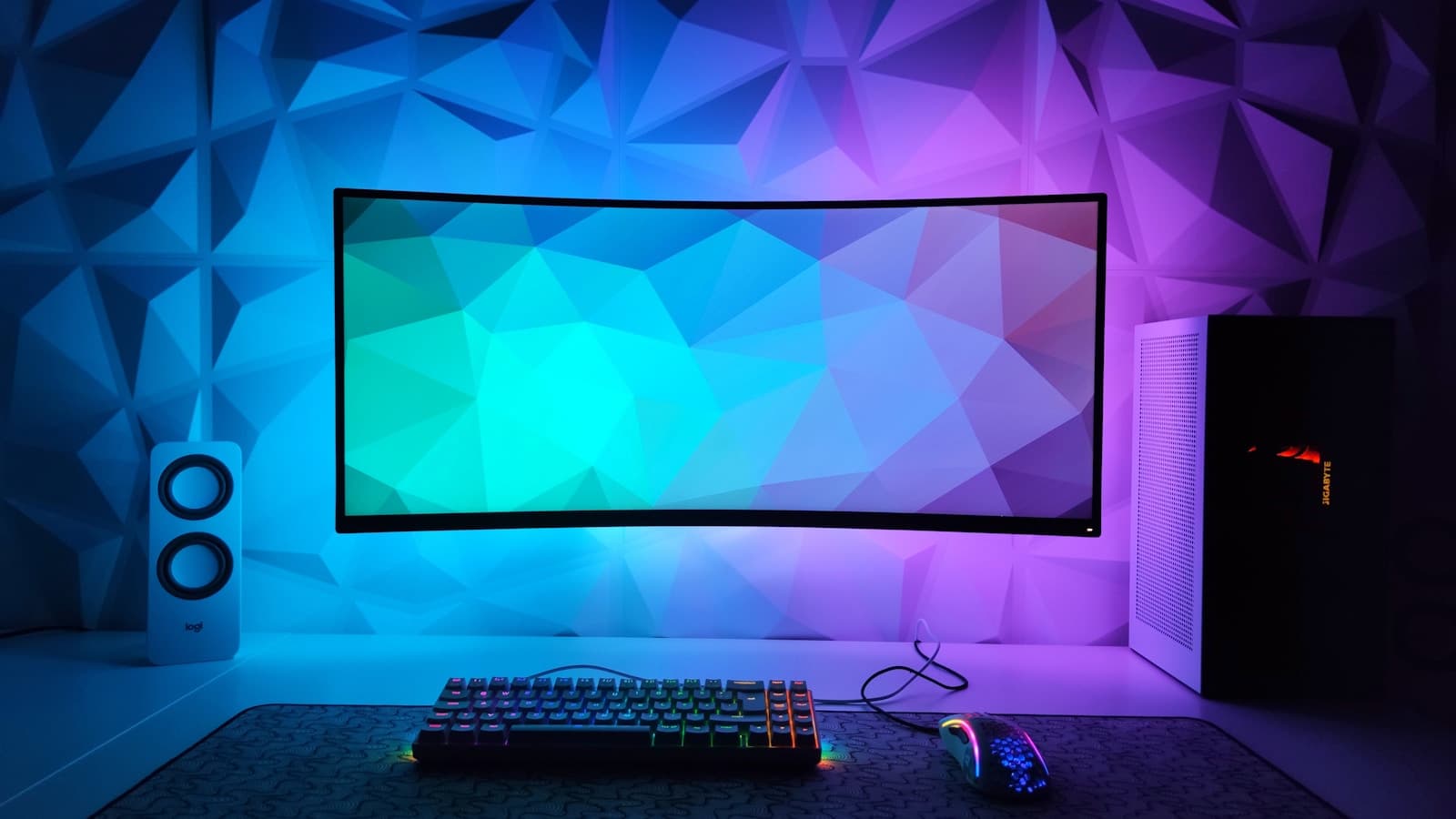 A modern desk setup with a wide-format monitor and ambient lighting.