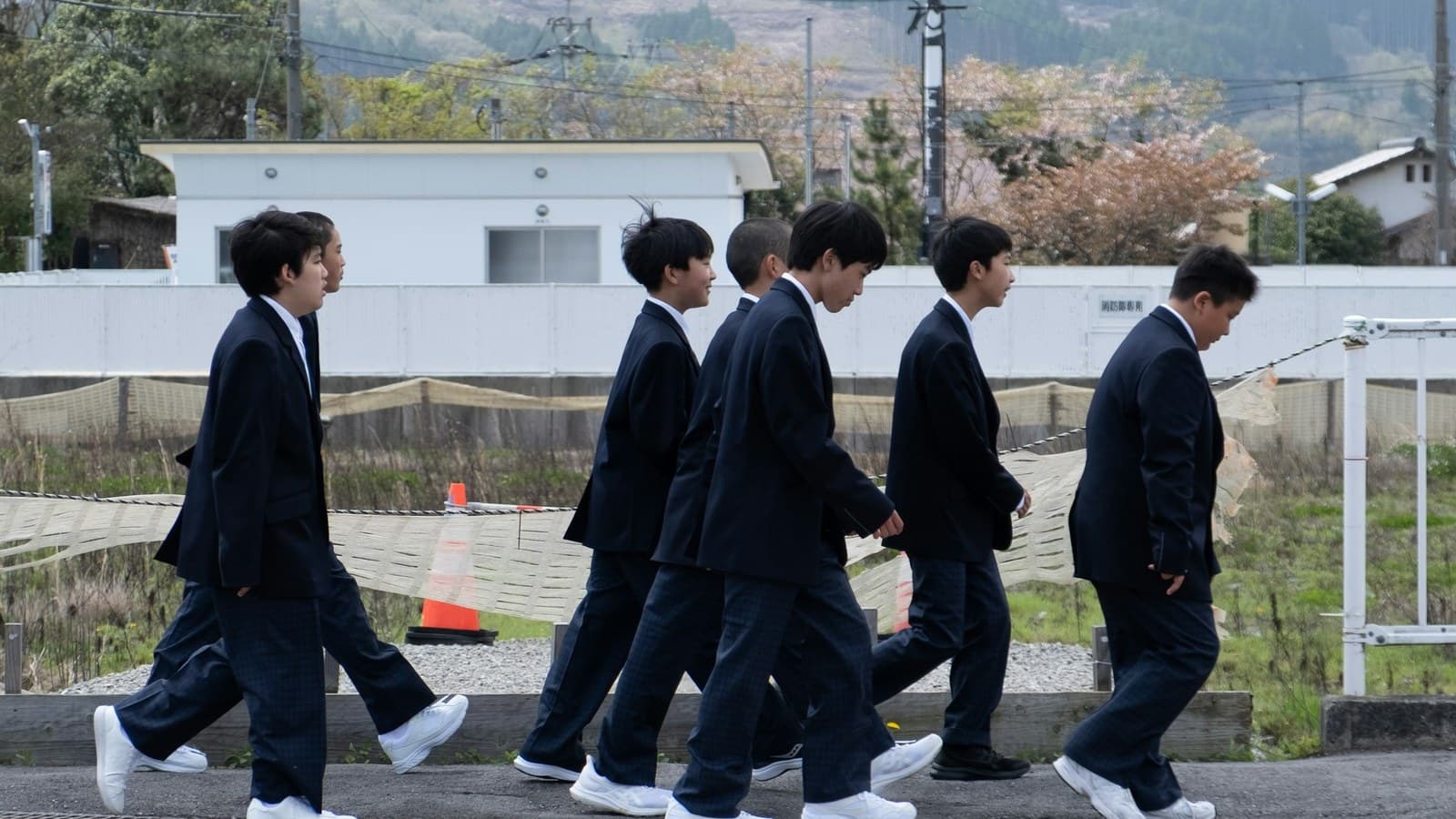 Students in matching uniforms walking together down a street.