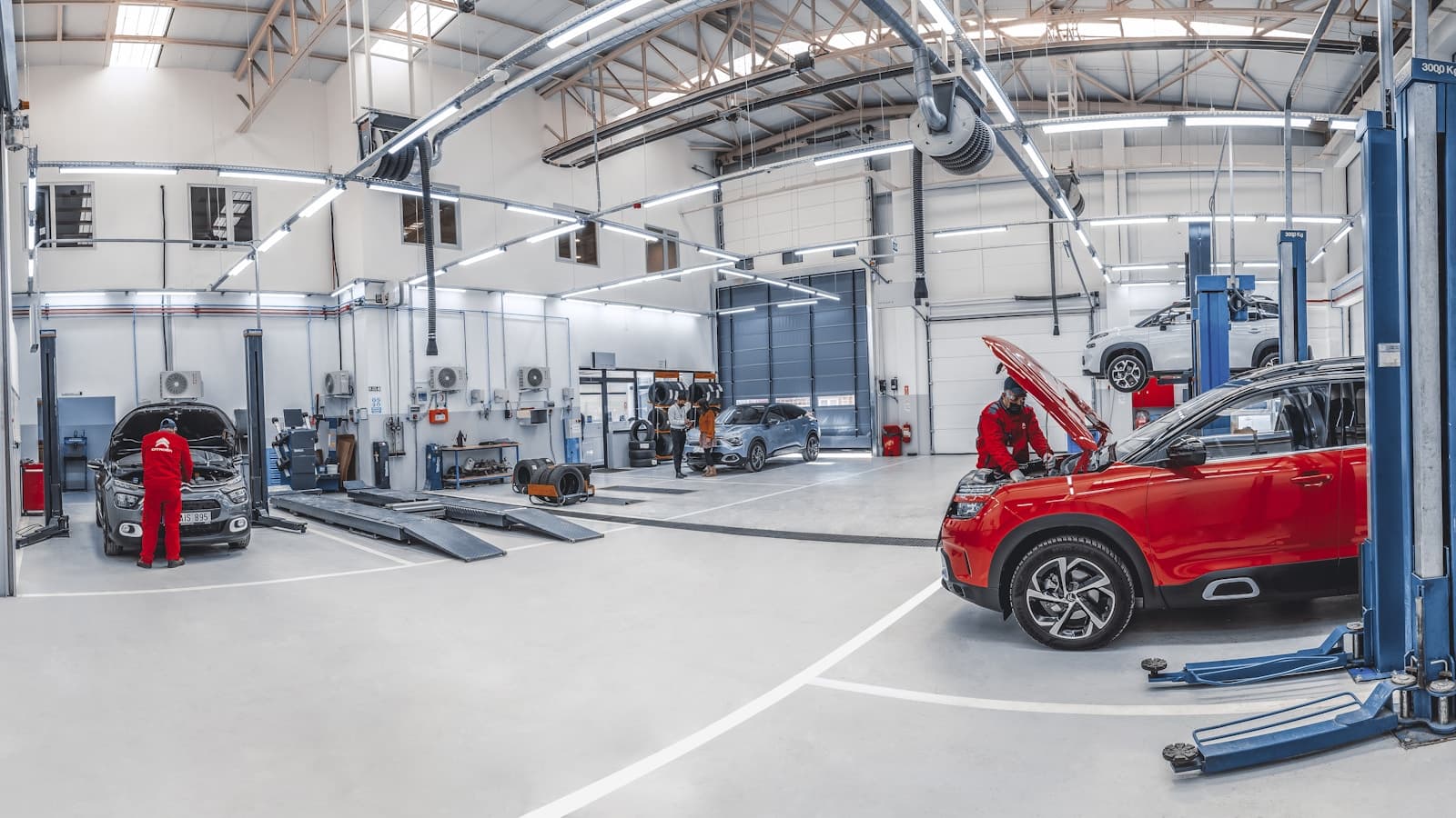 A wide, modern body shop with multiple vehicles on lifts.