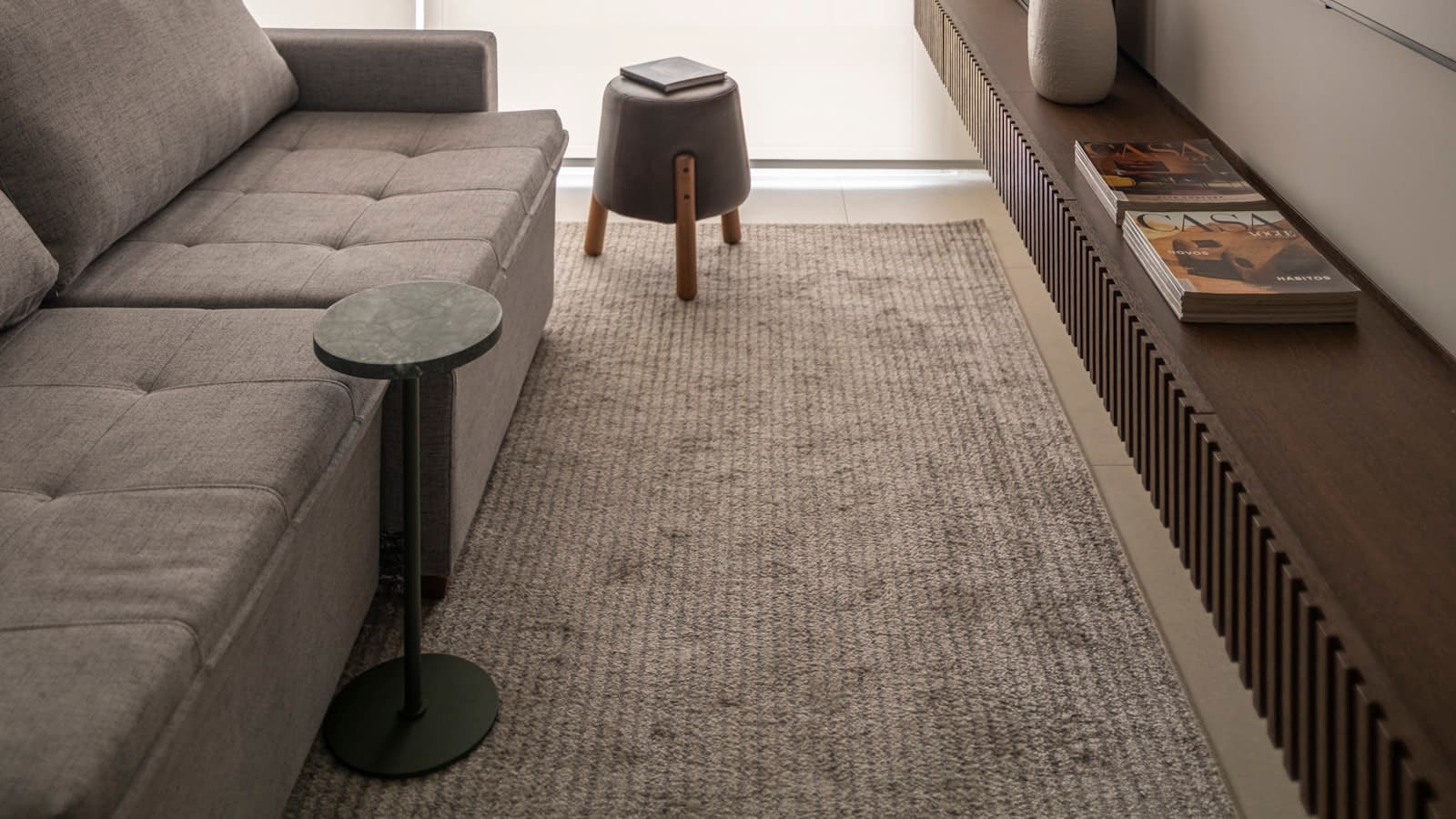 A minimalist living room with a gray sectional sofa and a mounted flat-screen TV, with no people or logos visible.