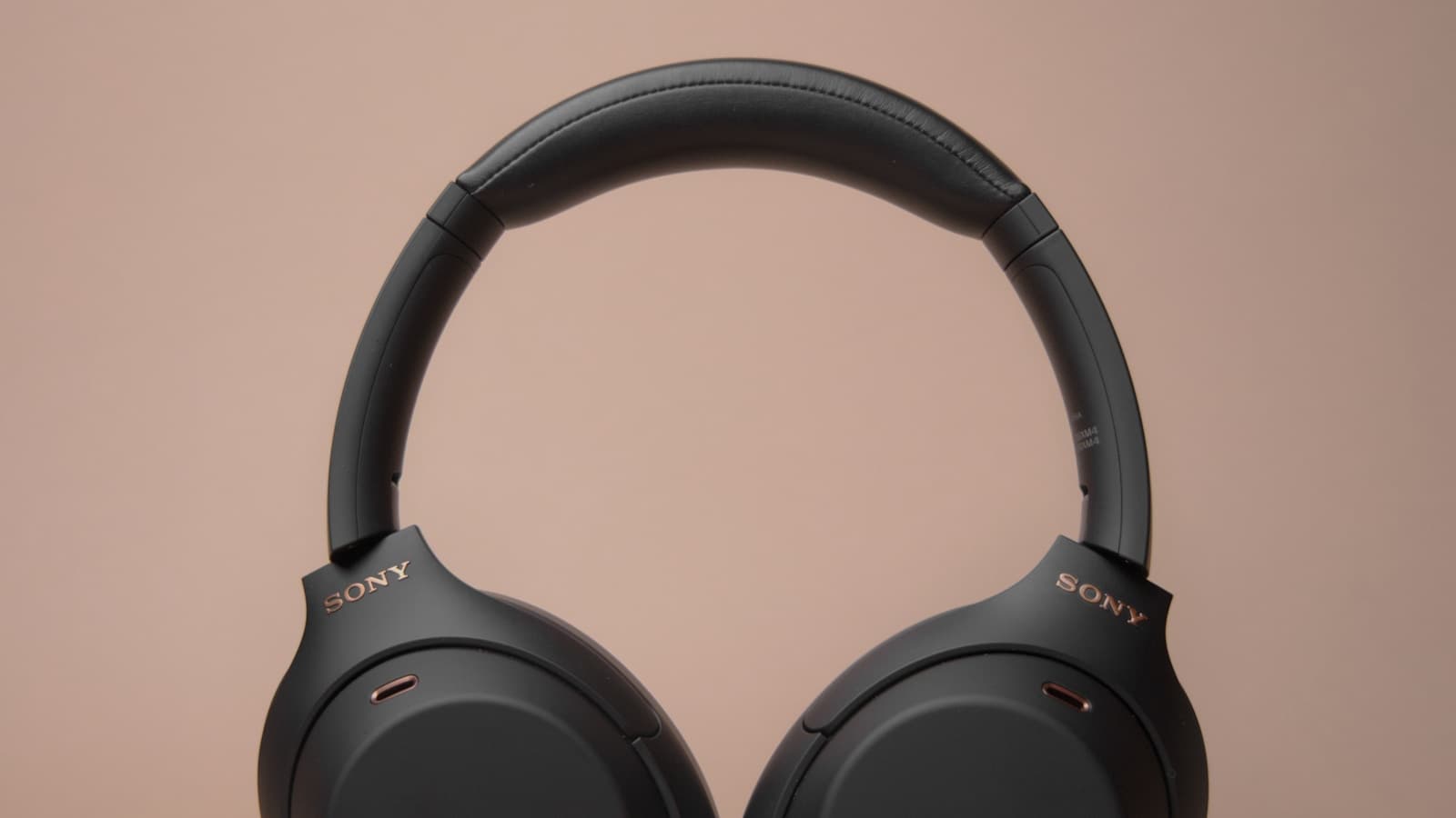 A pair of black over-ear wireless headphones on a plain white table.