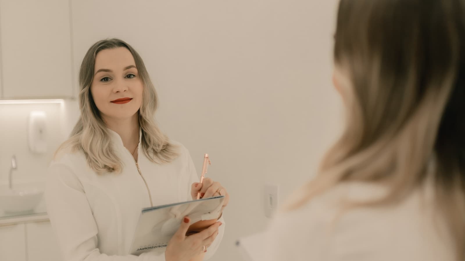 A woman in a robe examining her reflection in a mirror, calm clinical setting.