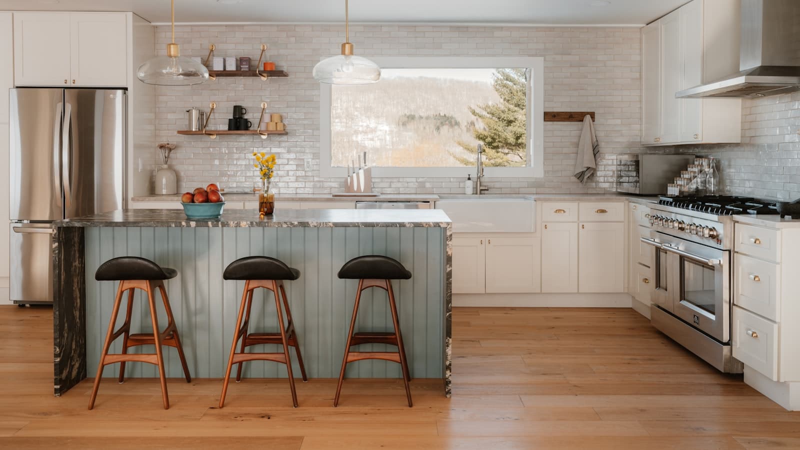 A bright modern kitchen with a stainless steel refrigerator, range, and island, with no people or readable text visible.