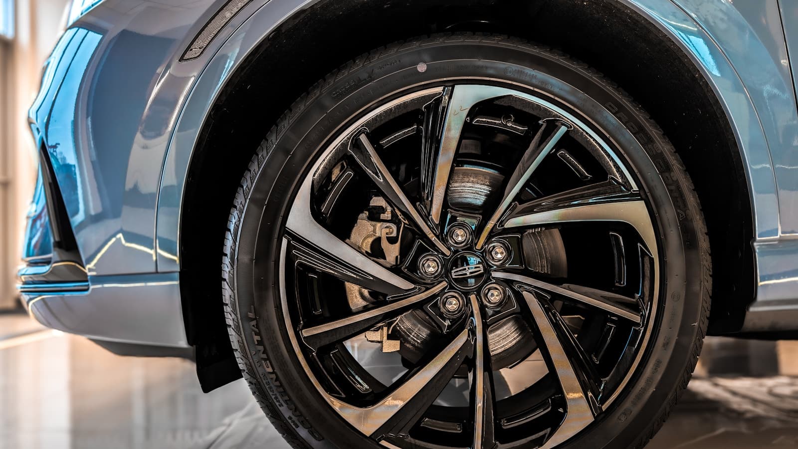 Close-up of a modern SUV's front wheel with a glossy multi-spoke rim and tire.