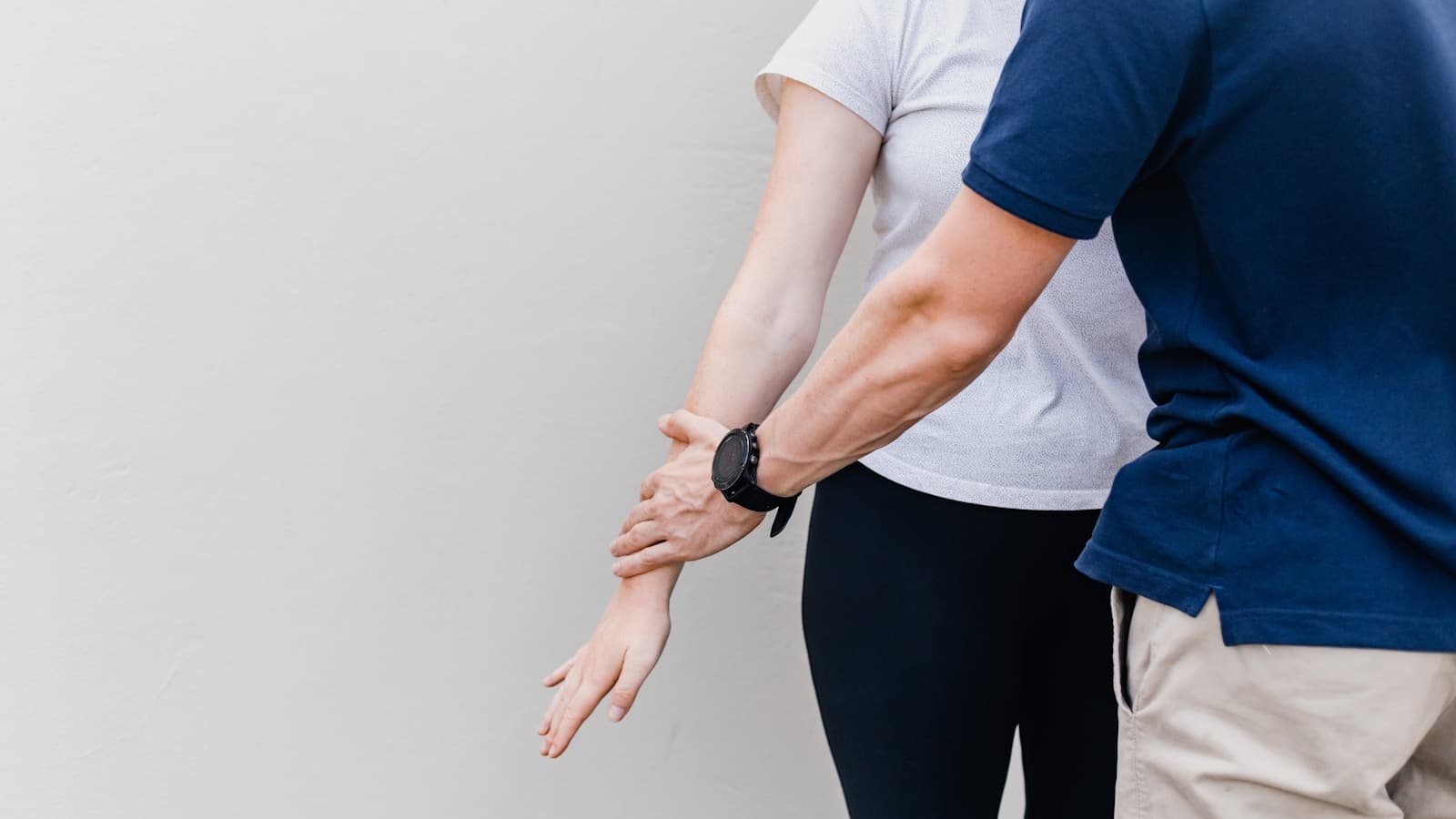 A physiotherapist gently guiding a patient's arm through a stretch.
