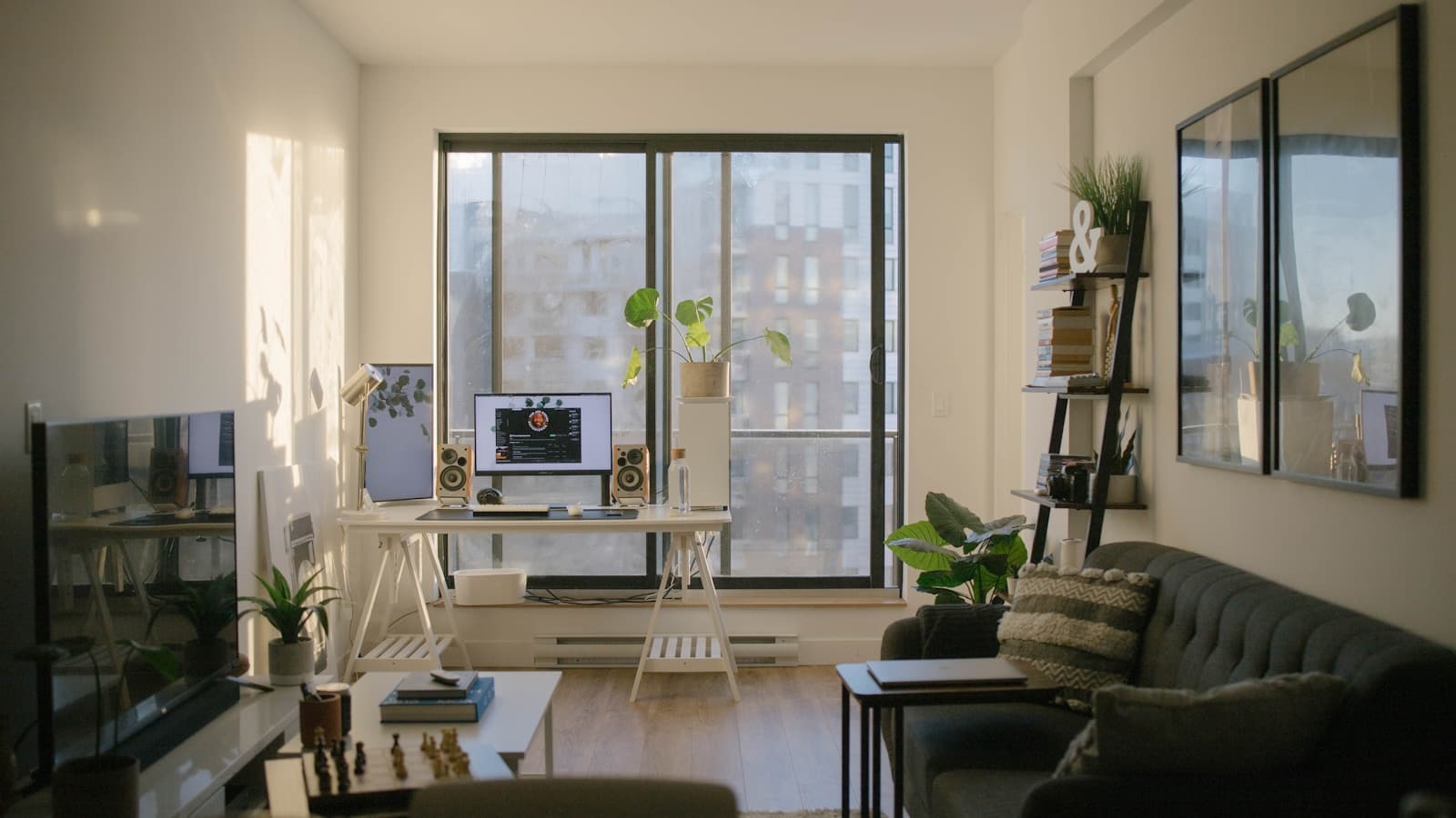 A cozy modern apartment living room with a desk setup, plants, and a sofa.