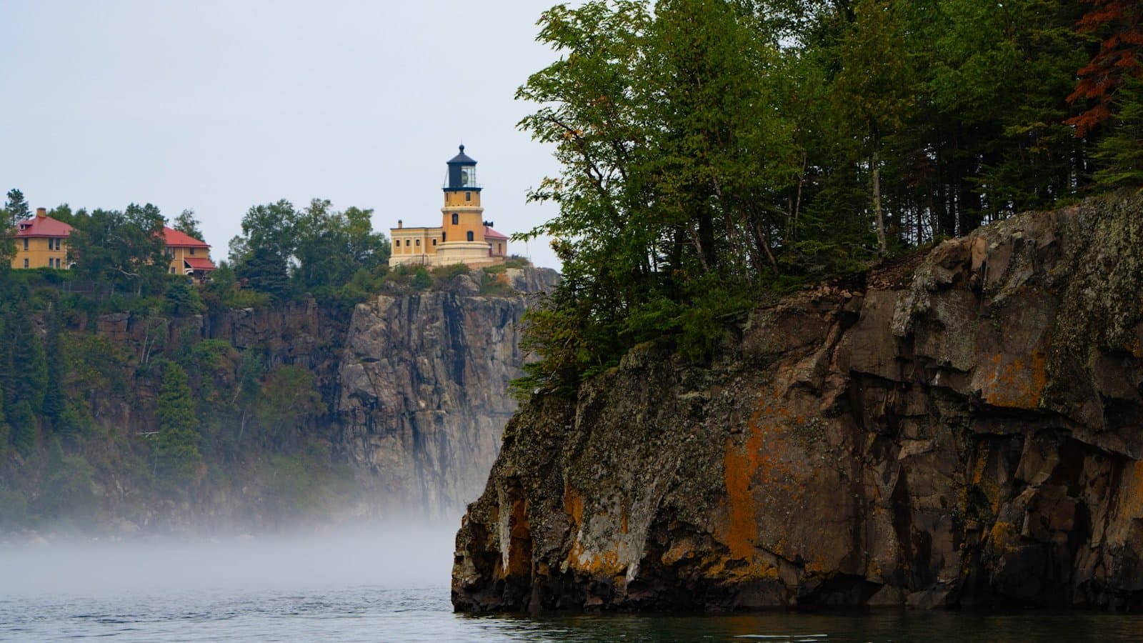 Split Rock Lighthouse perched on a rocky cliff above Lake Superior's North Shore, shrouded in morning mist.