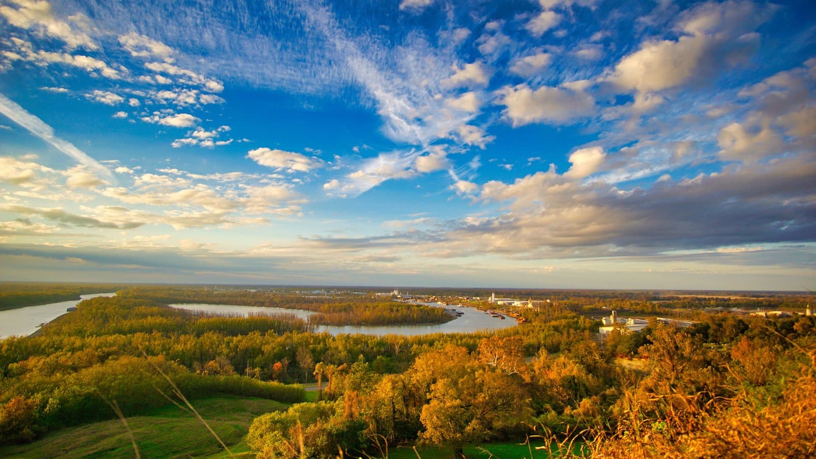 A golden-hour aerial view over the Mississippi River bend and forested bluffs near Vicksburg, Mississippi.