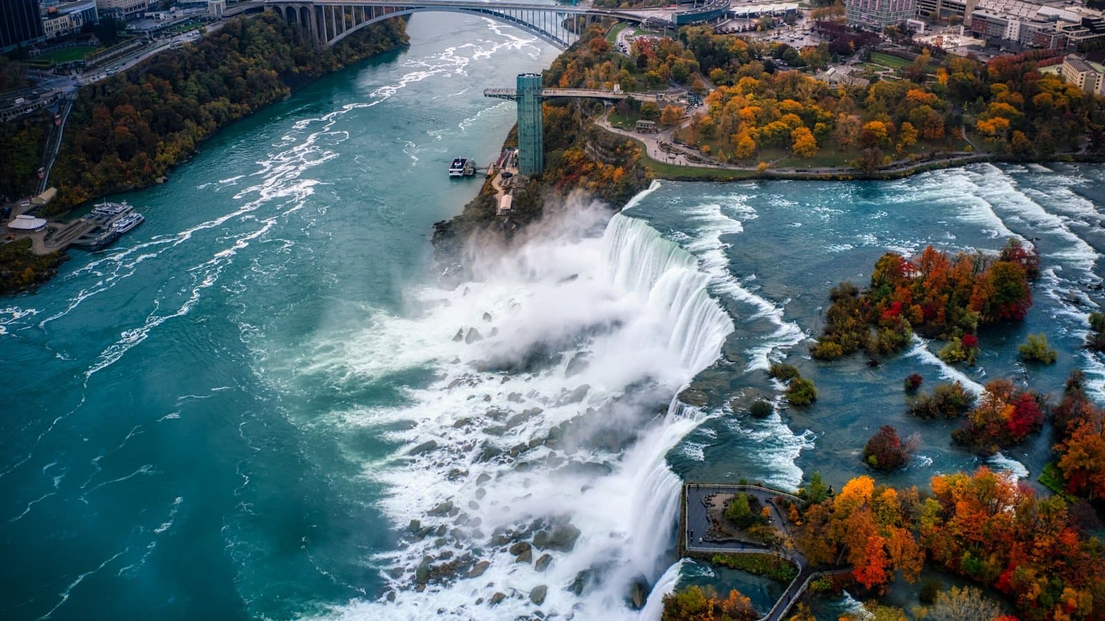 A dramatic aerial view of Niagara Falls in full autumn color.