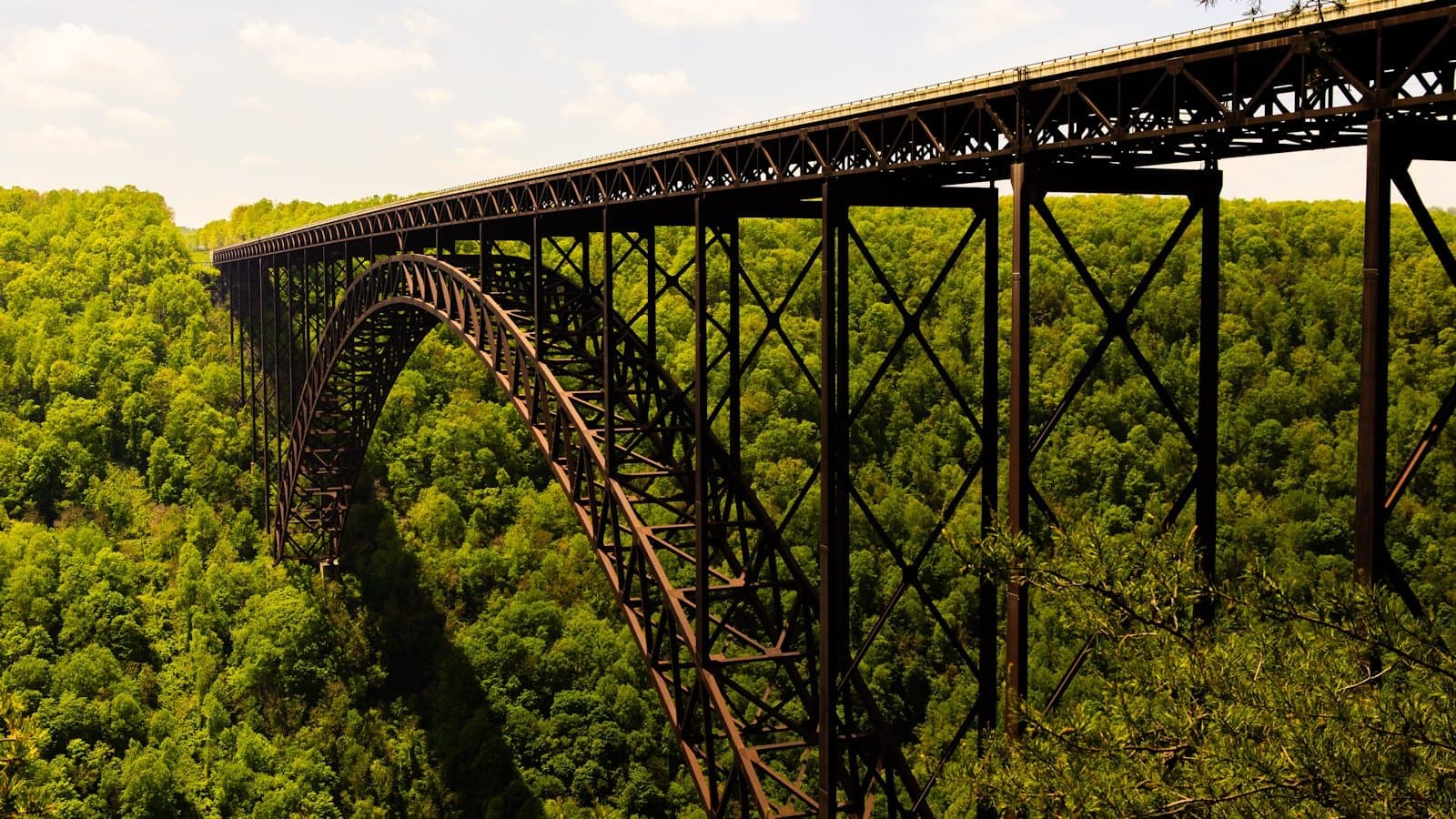 The New River Gorge Bridge's steel arch spanning a deep green forested gorge.