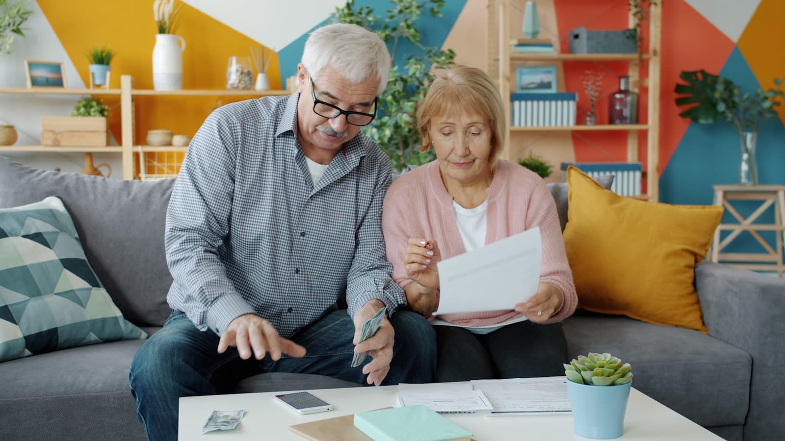 An older couple reviewing paperwork together at home on the couch.