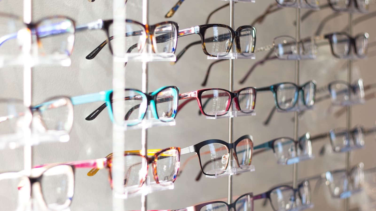 Rows of colorful eyeglass frames displayed on a rack at an optical shop.