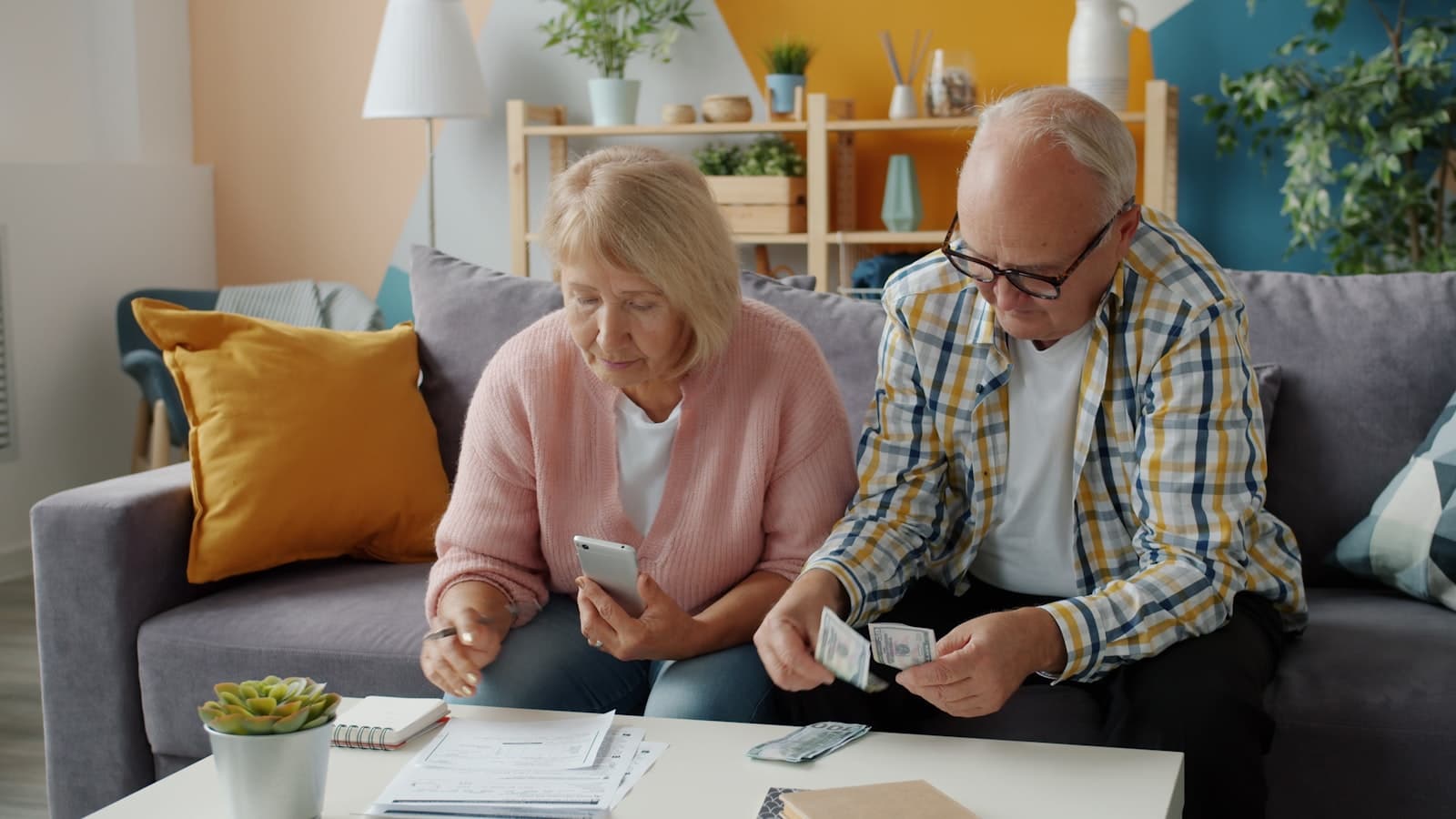 An older couple reviewing paperwork and counting cash together at home